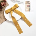 Detail of yellow bow hair clip with white pearls on a textured fabric ribbon - Yellow