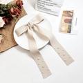 Close-up of elegant cream bow hair clip with pearls on a vintage ceramic display - Beige