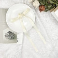 Vista dettagliata di un nastro di raso bianco crema con nodo a rosa su un piatto di ceramica - Fermaglio per Capelli Fiocco Rosa Beige Streamer Lungo / Beige