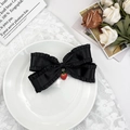Dettaglio di un fiocco per capelli in raso nero con pizzo e ciondolo a forma di fragola - Nero
