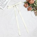 Elegant cream white satin bow hair clip with long ribbons on white textured background - Beige
