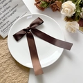 Détail de la barrette à nœud en satin marron café avec rubans sur plateau céramique - Marron