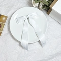 Detail einer weißen Satin-Schleife mit langen Bändern auf eleganter Geschenkverpackung - Weiß