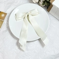 Detailansicht der eleganten cremeweißen Satinschleifen-Haarspange mit langen Bändern - Beige