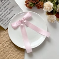 Roze satijnen strik haarspeld op een keramisch bord met een elegant bloemendecor - Roze