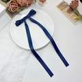 Gros plan d'une pince à cheveux à nœud bleu marine avec de longs rubans sur un plat blanc - Bleu marine