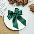 Elegante donkergroene satijnen haarclip met gouden bies op een wit sierbordje - Groen