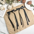 Detail van elegante zwarte satijnen strik haarspelden op een vintage papieren achtergrond - Zwart