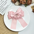 Detalle de un lazo de satén rosa multicapa con cintas largas en una escena elegante - Rosa