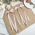 Elegant paar roze satijnen haarstrikken met lange linten tegen een rustieke achtergrond - Roze