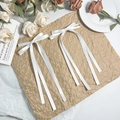 Elegante set van twee witte satijnen strik haarspelden met lange linten op een bloemrijke achtergrond - Wit