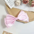 Detailed macro view of a large pink satin bow hair clip with glossy silk texture - Pink