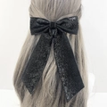 Fermaglio per capelli con grande fiocco nero glitterato e nastri su capelli biondi - Nero