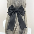 Detailansicht einer großen schwarzen Satin-Haarschleife mit eleganten langen Bändern im Haar - Schwarz