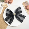Dettaglio di elegante fermaglio in pizzo nero con perla centrale su sfondo vintage - Fiore nero