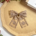 Close-up of vintage taupe lace hair clip with floral embroidery on a cork tray - Caramel color