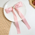 Détail d'une barrette à nœud en satin rose avec centre en cristal et longs rubans de soie - Rose