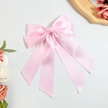 Nahaufnahme der rosa Satin-Haarschleife mit langen Bändern auf minimalistischem Grund - Rosa