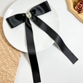 Détail d'un nœud en satin noir avec grand strass en cristal dans un plat blanc - Noir