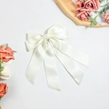 Detail einer eleganten cremefarbenen Satin-Haarschleife mit langen Bändern auf dem Tisch - Beige
