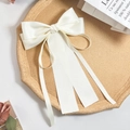 Détail d'un nœud papillon en satin ivoire avec de longs rubans sur un plateau - Blanc