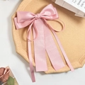 Détail d'une pince à cheveux à nœud en satin rose clair avec des rubans multicouches élégants - Rose