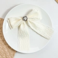 Close-up of cream lace bow hair clip featuring a sparkling heart crystal in the center - Ivory