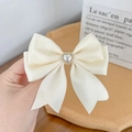 Dettaglio del fiocco in raso crema con perla a forma di cuore e bordo dorato - Beige