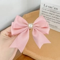 Detail of pink bow hair clip with a centered heart pearl and gold bead accents - Pink