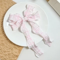 Detail der rosa-weißen Haarklammer mit Karomuster, Faltenstruktur und langen Bändern - Rosa