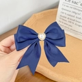 Detailed view of a navy silk bow hair clip with an elegant heart pearl embellishment - Navy Blue
