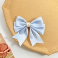 Detail of light blue satin bow hair clip with a central pearl heart on a tray - Blue