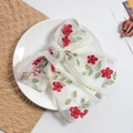 Détail d'un nœud papillon en dentelle blanche avec broderie florale sur une assiette - Broderie Florale Rouge