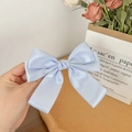 Detail view of light blue satin bow hair clip held against a French vintage background - Light Blue