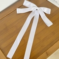 Detailopname van de witte satijnen haarclip met lange linten op een houten dienblad - Wit