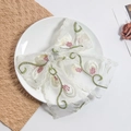 Vue détaillée du nœud en dentelle blanche avec broderie de vignes vertes et fleurs roses - Broderie de Bouton Rose
