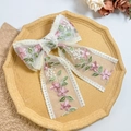 Détail d'une pince à cheveux en dentelle blanche avec broderie florale et longs rubans - Style Ruban Fleur Rose