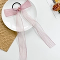 Detalle de coletero rosa claro con lazo de malla y cintas largas en un plato blanco - Rosa