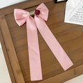 Detalle del pasador de lazo de satén rosa con rosa roja y cintas largas sobre bandeja bambú - Rosa