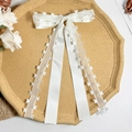 Detalle del pasador con lazo de satén blanco y organza con patrones de corazones - Beige