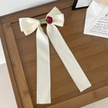 Detalle de un lazo de satén crema con rosa roja y cintas largas decorativas - Blanco Roto