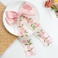 Detail einer rosa Schleifen-Haarspange mit floraler Stickerei auf Spitzenbändern im Tablett - Satin Bestickter Langer Band Stil-Rosa