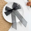 Detail of elegant black mesh bow hair clip with long ribbons on a white porcelain plate - Black