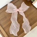 Détail d'une pince à cheveux en tulle rose avec de longs rubans sur plateau bois - Rose