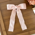 Elegante pinza de pelo con lazo jacquard rosa y cintas largas sobre fondo madera - Rosa