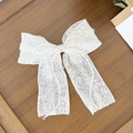 Detail of white lace bow hair clip with pearl edges and a crystal heart center - Beige