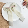 Detail van de crèmekleurige satijnen haarstrik met borduursel van kersenbloesems - Roze