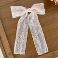 Detailed texture of pink lace bow hair clip with ribbons on a rustic wood background - Pink