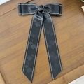 Detail of black satin bow hair clip with clover pattern and white stitched edges - Black