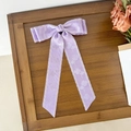 Detail der lavendelfarbenen Haarschleife mit Blumenmuster und Wellenrand-Design - Lila